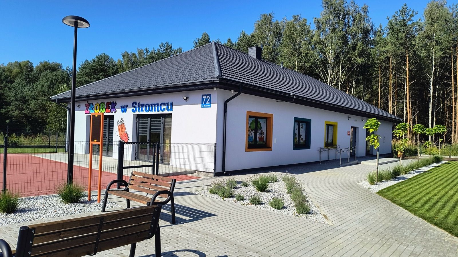 Budynek Publicznego Żłobka w Stromcu od strony ulicy, z kolorowym szyldem i placem zabaw obok wejścia