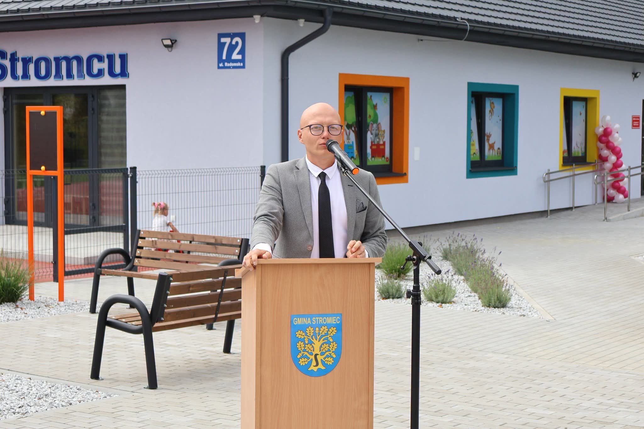 Przemówienie przy mównicy z herbem Gminy Stromiec, przed wejściem do żłobka